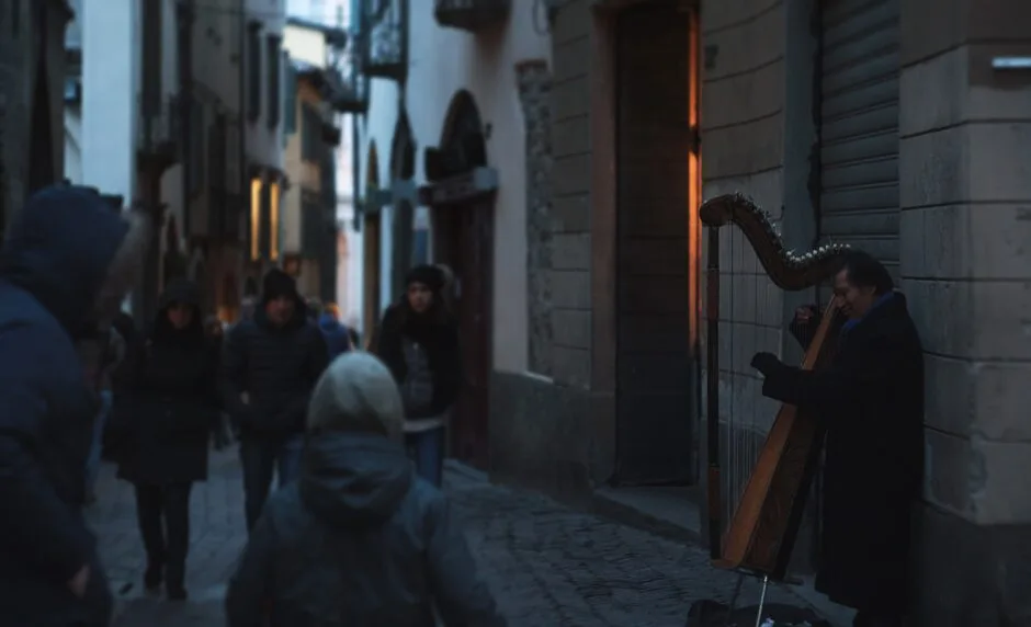man playing musical instrument near brown brick wall during daytime