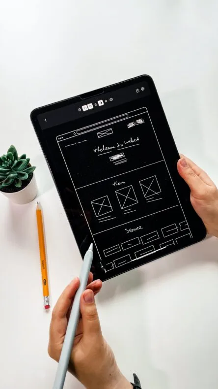 person holding black ipad with green plant